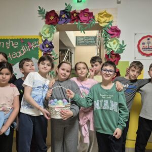 Familie fericită cu copii pregătind masa pentru Paștele ortodox, vopsind ouă și zâmbind în bucătărie.